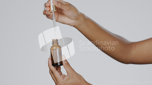 Image of Serum, dropper and hands in skincare or beauty, health and wellness or dermatology. Hyaluronic acid, hydration and skin and cosmetics with vitamin c, self care and luxury in studio by gray background