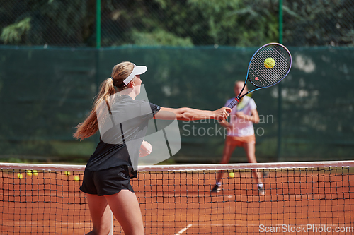 Image of Young girls in a lively tennis match on a sunny day, demonstrating their skills and enthusiasm on a modern tennis court.