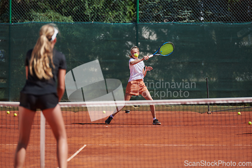 Image of Young girls in a lively tennis match on a sunny day, demonstrating their skills and enthusiasm on a modern tennis court.