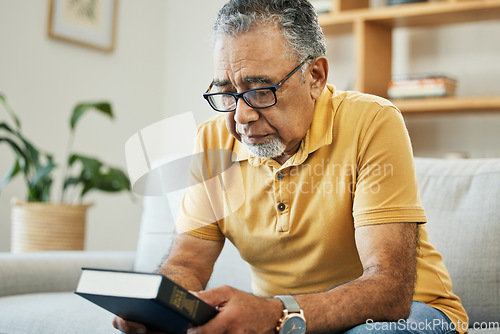 Image of Man, holding and book in thought at home, memory and alone for comfort in hope. Male, person or grandfather on sofa in living room with thoughts of bible, religion or church in prayer for support