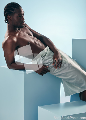 Image of Body, relax and black man in studio for wellness, grooming or self care against a blue background. Topless, muscle and African male model posing with cosmetic care, treatment or fine art aesthetic