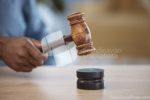 Image of Gavel, hand of lawyer or judge in office for decision, attention or legal advice in justice system. Hammer, desk and person in courtroom, law firm or government agency to stop hearing in human rights