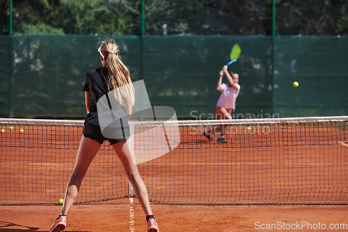 Image of Young girls in a lively tennis match on a sunny day, demonstrating their skills and enthusiasm on a modern tennis court.