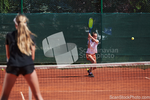 Image of Young girls in a lively tennis match on a sunny day, demonstrating their skills and enthusiasm on a modern tennis court.