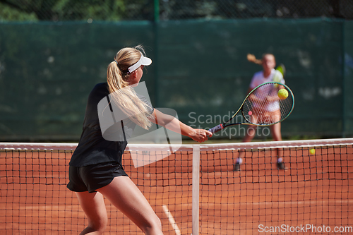 Image of Young girls in a lively tennis match on a sunny day, demonstrating their skills and enthusiasm on a modern tennis court.