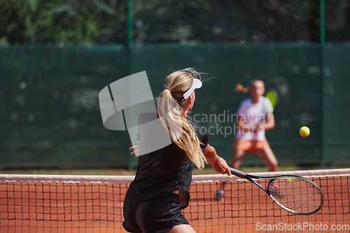 Image of Young girls in a lively tennis match on a sunny day, demonstrating their skills and enthusiasm on a modern tennis court.