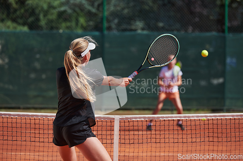 Image of Young girls in a lively tennis match on a sunny day, demonstrating their skills and enthusiasm on a modern tennis court.