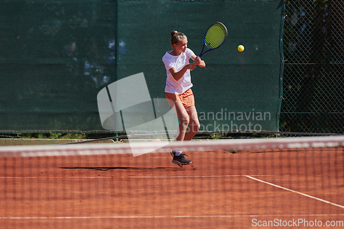 Image of Young girls in a lively tennis match on a sunny day, demonstrating their skills and enthusiasm on a modern tennis court.