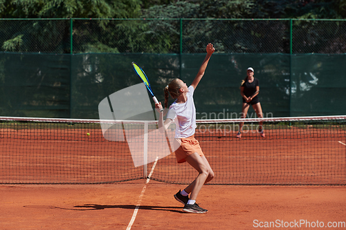 Image of Young girls in a lively tennis match on a sunny day, demonstrating their skills and enthusiasm on a modern tennis court.