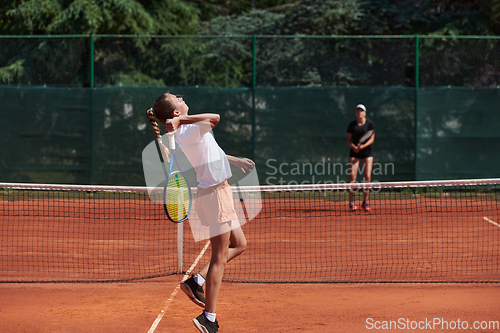 Image of Young girls in a lively tennis match on a sunny day, demonstrating their skills and enthusiasm on a modern tennis court.