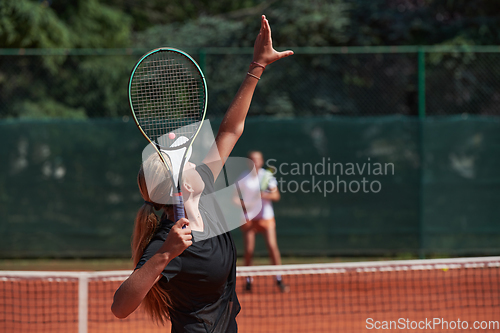 Image of Young girls in a lively tennis match on a sunny day, demonstrating their skills and enthusiasm on a modern tennis court.