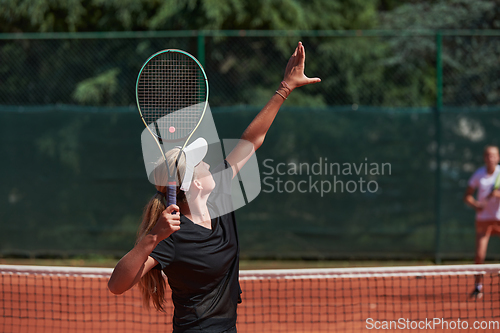 Image of Young girls in a lively tennis match on a sunny day, demonstrating their skills and enthusiasm on a modern tennis court.