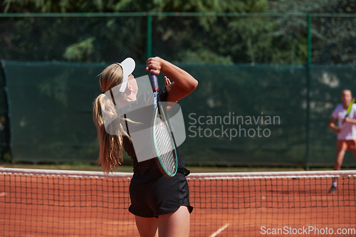 Image of Young girls in a lively tennis match on a sunny day, demonstrating their skills and enthusiasm on a modern tennis court.