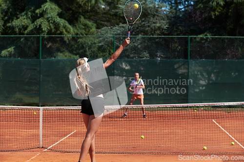 Image of Young girls in a lively tennis match on a sunny day, demonstrating their skills and enthusiasm on a modern tennis court.