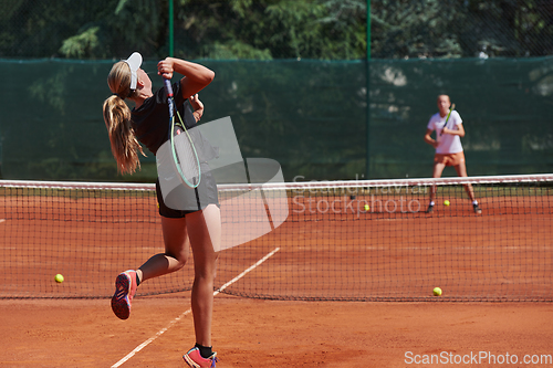 Image of Young girls in a lively tennis match on a sunny day, demonstrating their skills and enthusiasm on a modern tennis court.