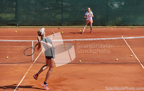 Image of Young girls in a lively tennis match on a sunny day, demonstrating their skills and enthusiasm on a modern tennis court.