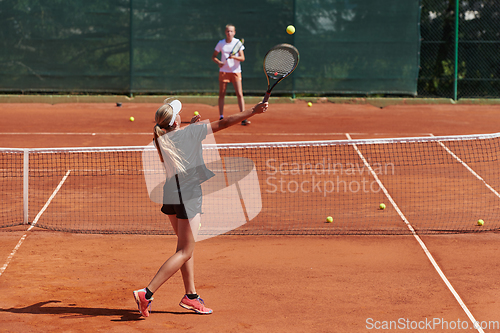 Image of Young girls in a lively tennis match on a sunny day, demonstrating their skills and enthusiasm on a modern tennis court.