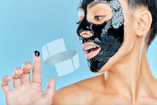 Image of Skincare, charcoal mask and finger of woman for facial treatment, anti aging detox and wellness. Beauty, studio and person with face products for health, cosmetics or grooming on blue background