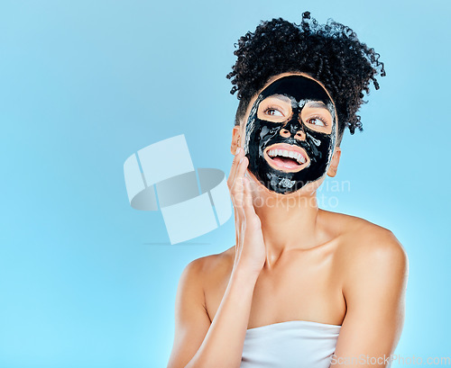Image of Skincare, happy and woman with charcoal face mask for facial treatment, anti aging and wellness in studio. Beauty, dermatology and happy person for health, cosmetics or grooming on blue background