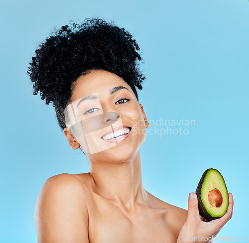 Image of Happy woman, portrait and avocado for natural beauty, skincare or diet against a blue studio background. Face of female person smile with organic vegetable for nutrition, vitamin C or skin wellness