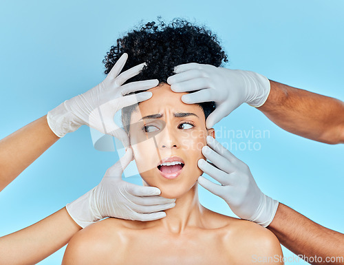 Image of Plastic surgery, facial and scared woman with hands on face in studio for skincare consultation. Model with stress, fear and anxiety for beauty, dermatology or collagen therapy on blue background.