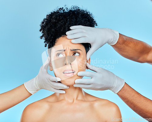 Image of Skincare, plastic surgery and fear, woman with hands on face in studio for cosmetic consultation. Model with stress, worry and anxiety for beauty, dermatology or collagen therapy on blue background.
