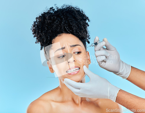 Image of Filler, fear and woman with hands on face in studio for collagen skincare injection or implant. Model with stress, anxiety and syringe for beauty, dermatology or cosmetic process on blue background.