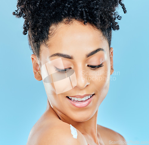 Image of Skincare, face and happy woman with body cream, lotion or moisturizer for self care, collagen treatment or skin hydration. Sunscreen protection, shoulder and studio model smile on blue background