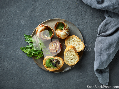 Image of plate of baked escargot snails filled with parsley and garlic bu