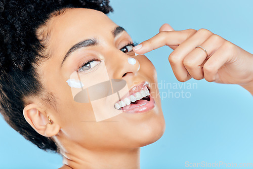 Image of Beauty skincare, portrait and happy woman with cream application of dermatology product for pimple, acne or spots prevention. Face makeup, studio cosmetics or aesthetic person on blue background
