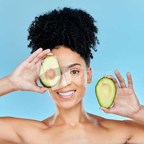 Image of Happy woman, portrait and avocado for skincare, diet or natural beauty against a blue studio background. Face of female person smile with organic fruit for nutrition, vitamin C or skin wellness