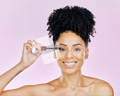 Image of Portrait, beauty and mascara with a woman on a pink background in studio to apply makeup or cosmetics. Smile, skincare and face product with a happy young model on color for eyelash cosmetology