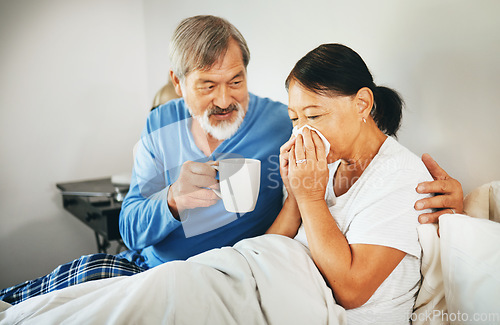 Image of Sick senior woman in bed with husband blowing her nose with tissue for flu, allergies or cold. Love, comfort and elderly man in retirement hugging his ill wife in bedroom of modern home on a weekend.