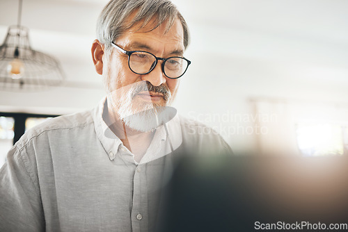 Image of Laptop, serious and senior man in home on social media, internet search or remote work. Computer, reading and elderly freelancer on website, communication and online on digital technology in house