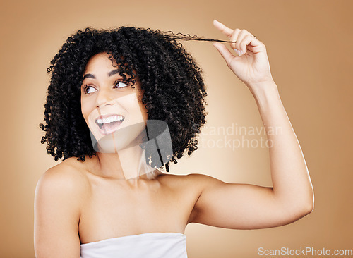 Image of Happy, thinking and a woman with an afro, hair care or stretching a hairstyle on a studio background. Smile, excited and a model or young girl with a style, grooming or idea for curls on a backdrop