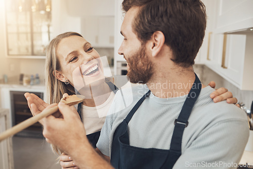 Image of Cooking, taste and happy couple in kitchen bonding while preparing a meal in their home together. Food, spoon and man feeding woman in a house with romance, smile and having fun on weekend or day off