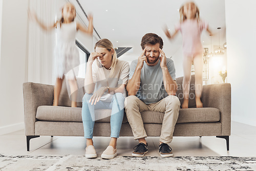 Image of Frustrated parents, sofa and headache with children jumping in living room chaos, ADHD or crazy home. Mother and father in stress, burnout or fatigue with busy or hyper active kids in lounge at house