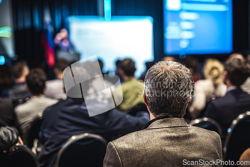 Image of Speaker giving a talk in conference hall at business event. Rear view of unrecognizable people in audience at the conference hall. Business and entrepreneurship concept.