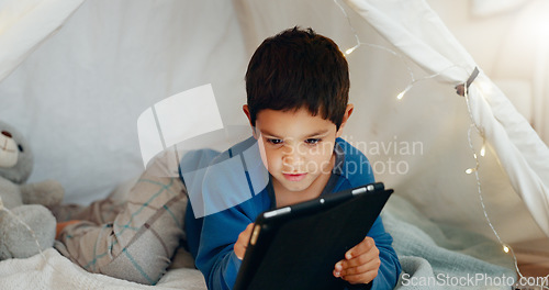 Image of Tablet, relax and boy child in a tent playing an online game on the internet in the living room. Happy, entertainment and kid watching a movie, video or show on a digital technology in a blanket fort