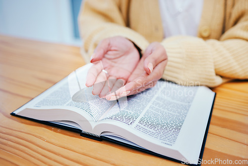 Image of Hands, bible and prayer at desk, religion and Christian worship in home at table. Closeup, holy book and woman in meditation for God, Jesus and Christ for faith in spiritual gospel, praise or hope