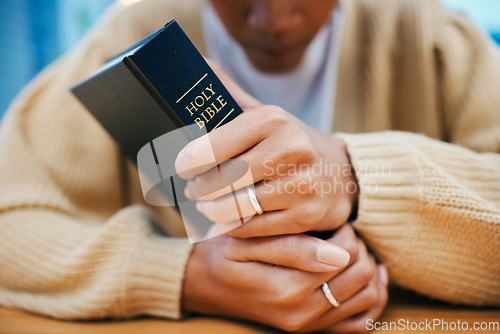 Image of Hands, bible and prayer at desk, religion and Christian worship in home at table. Closeup, holy book and woman in meditation for God, Jesus and Christ for faith in spiritual gospel, praise or hope