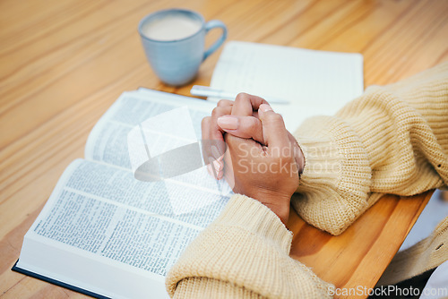 Image of Hands, bible and praying at table, religion and Christian worship in home at desk. Closeup, holy book and woman in meditation for God, Jesus and Christ for faith in spiritual gospel, praise or hope