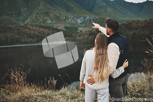 Image of Couple, relax and pointing to mountain for hiking, camping or nature for outdoor scenery together. Rear view of man and woman hug enjoying holiday vacation, travel trip or trekking adventure outside