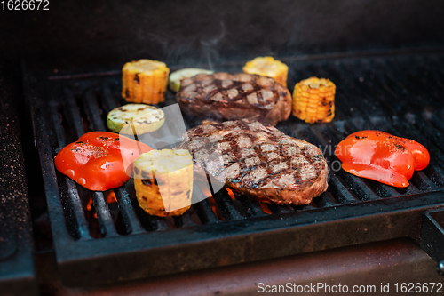 Image of Beef steaks on the grill with flames