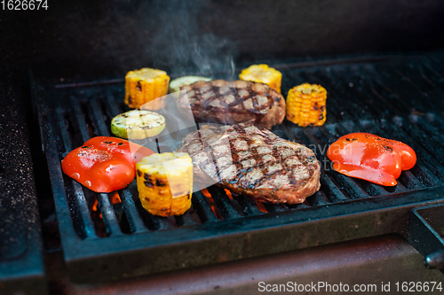 Image of Beef steaks on the grill with flames