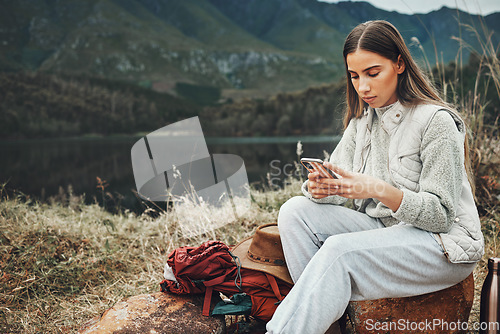Image of Nature, phone and young woman hiking on a mountain and network on social media or mobile app. Travel, technology and female person from Canada scroll on internet with cellphone in outdoor forest.