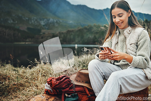 Image of Nature, smile and woman on a phone for hiking on a mountain and network on social media or mobile app. Happy, technology and young female person scroll on internet with cellphone in outdoor forest.