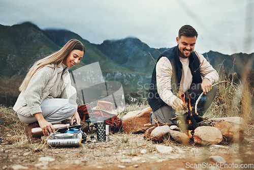 Image of Couple, camping and fire in nature, mountains and outdoor for sustainable heating, vacation and prepare kettle. Happy man and woman in field with water, campfire or flames for cooking on holiday