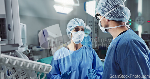 Image of Medical team, people and doctor in operating room to talk, strategy and pointing at screen for surgery. Man, woman and scrubs in healthcare with equipment in theatre with monitor for xray of patient