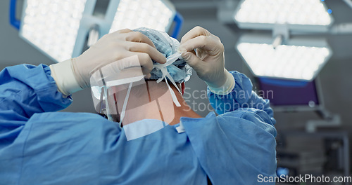 Image of Surgery, prepare and doctor tie mask in operating room for medical service, protection and operation. Healthcare team, safety scrubs and person with uniform for emergency, procedure and wellness